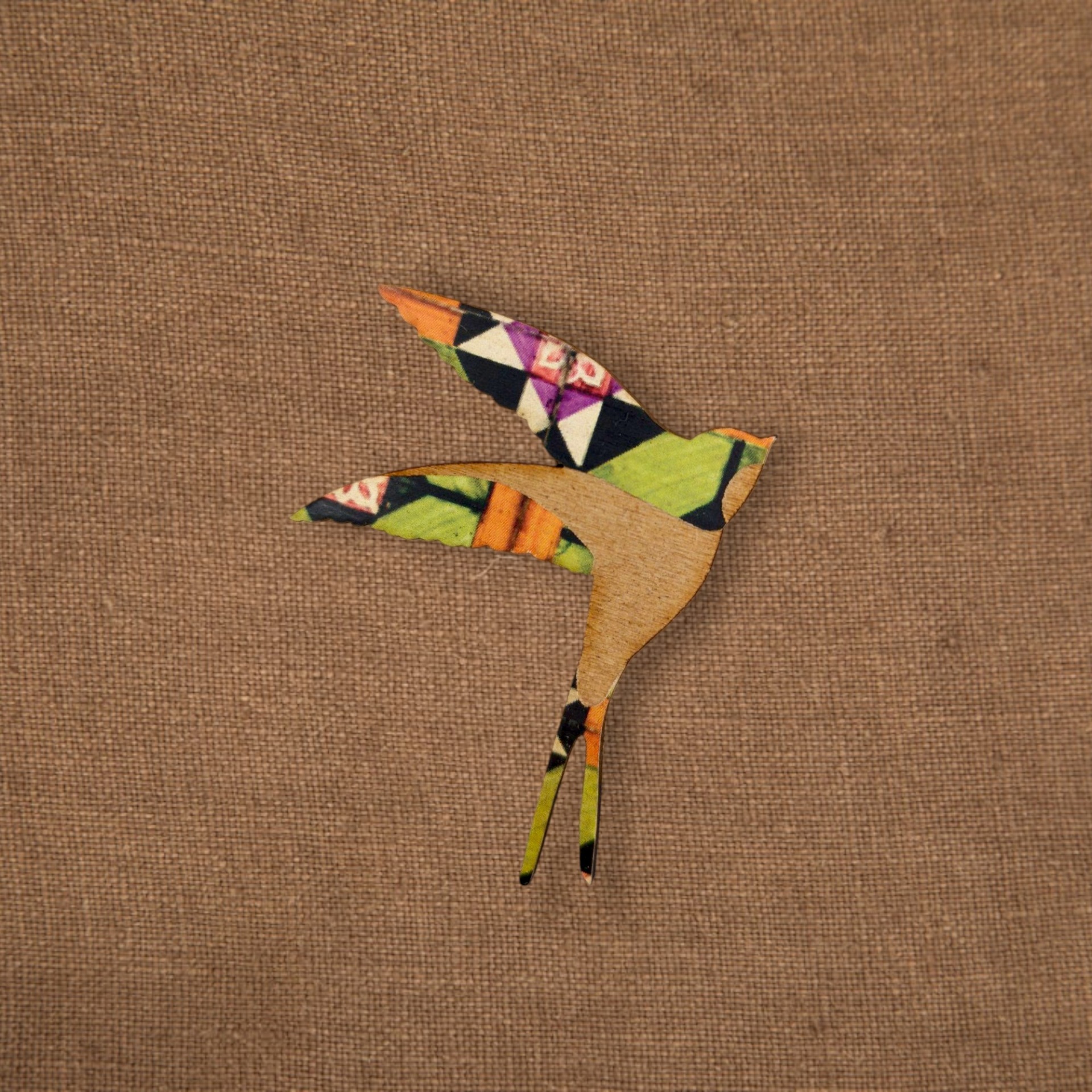 Pregadeira Andorinha Azulejo Pássaro decorativo em madeira com asas de tecido colorido em fundo castanho