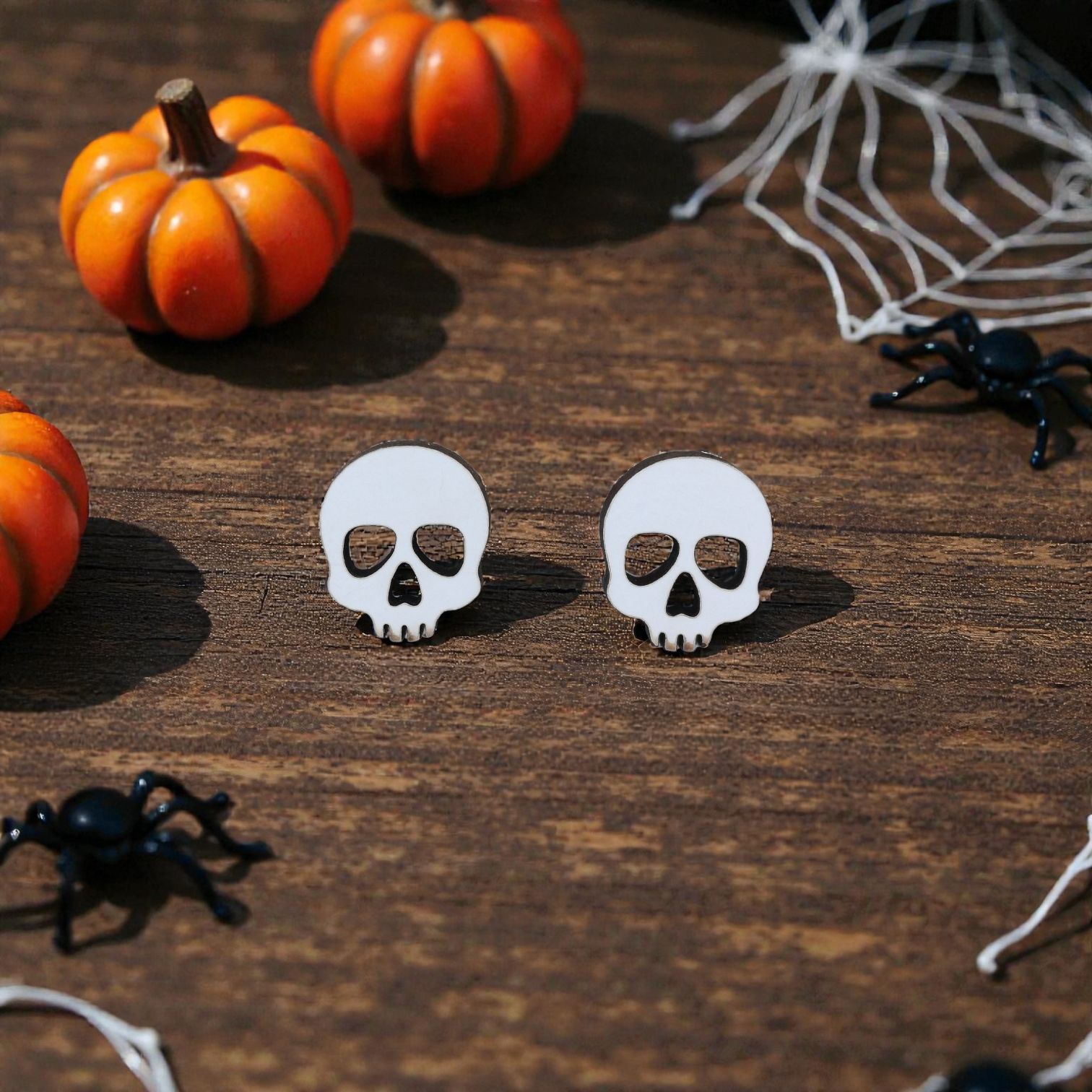Brincos Caveira Par de brincos caveira branca com contorno preto sobre madeira com decoração de Halloween