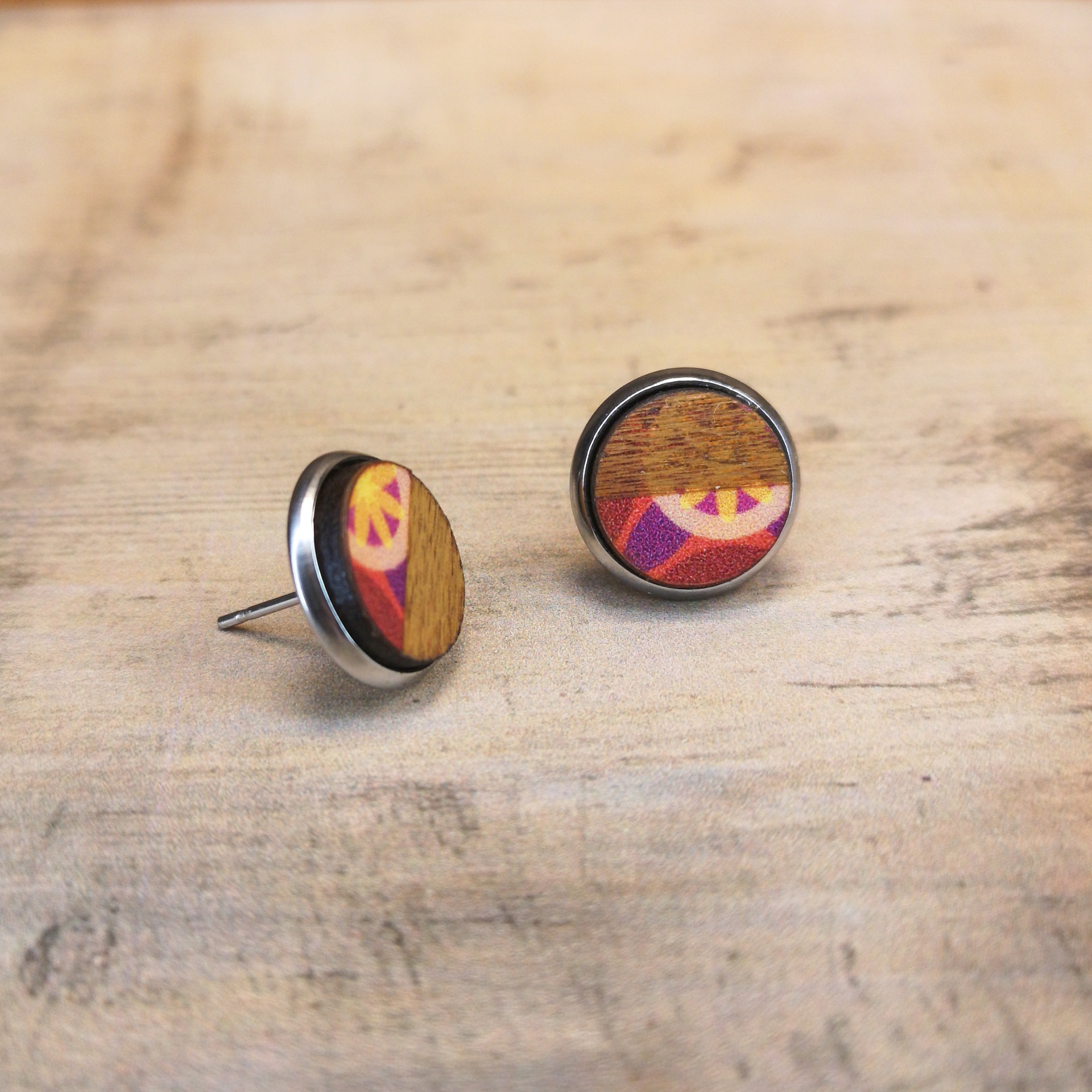 Brincos Círculo Brincos tipo tacha redondos com madeira e padrão geométrico colorido.