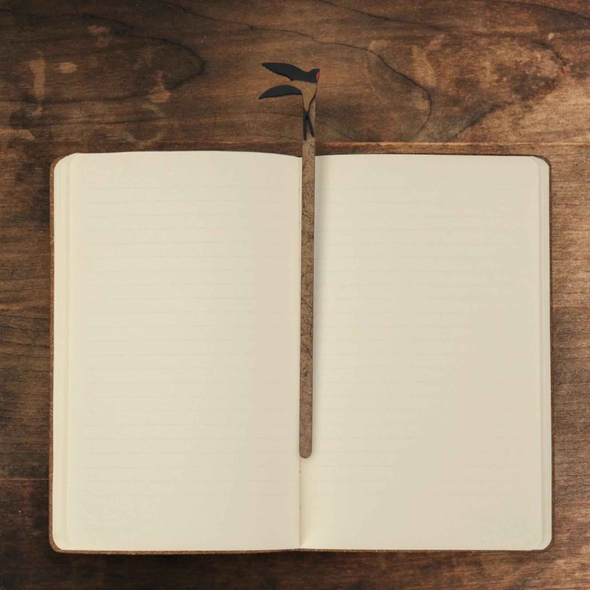 Marcador Andorinha Caderno aberto com páginas pautadas e lápis sobre mesa de madeira