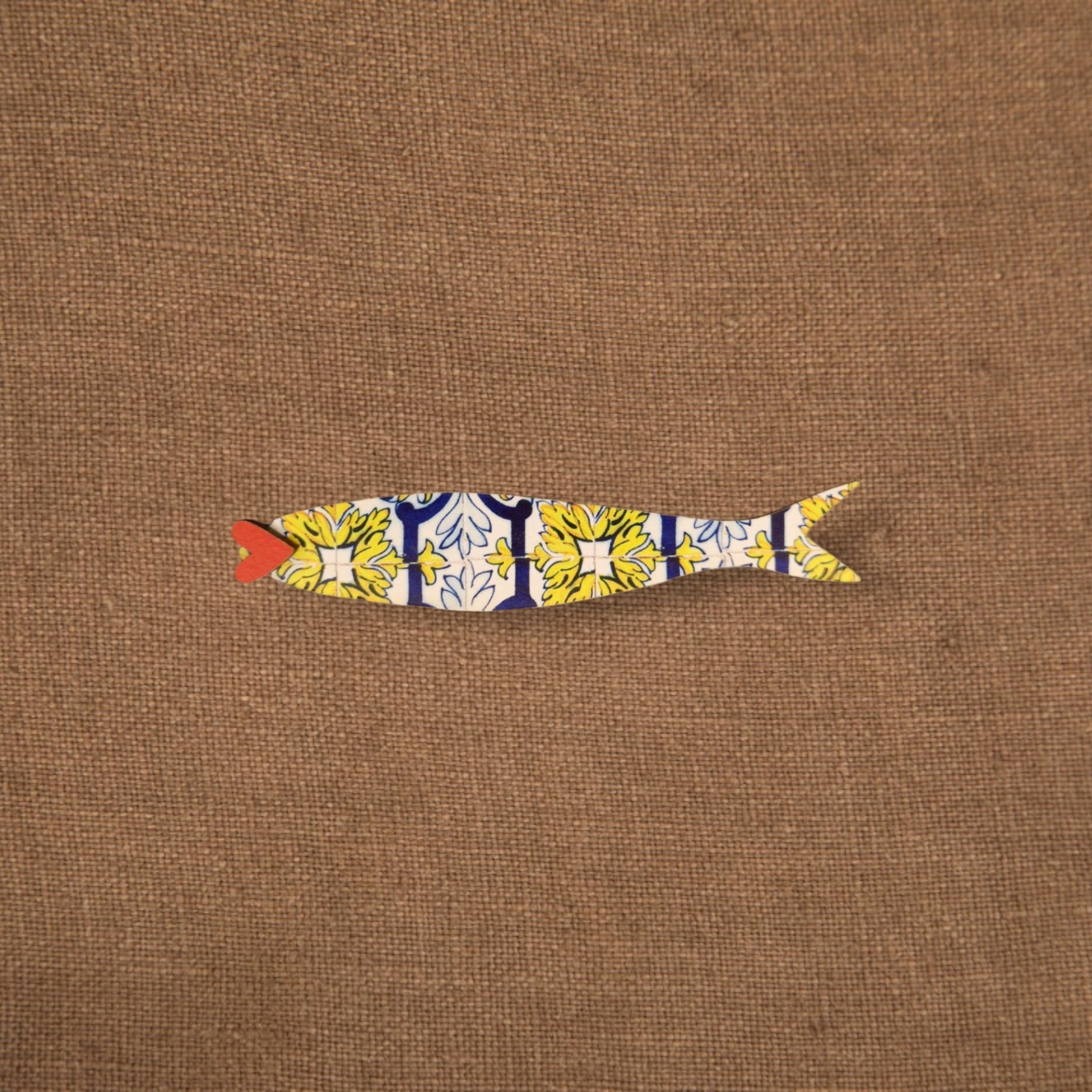 Pregadeira Sardinha Azulejo Peixe decorativo em madeira com padrão colorido sobre fundo castanho.