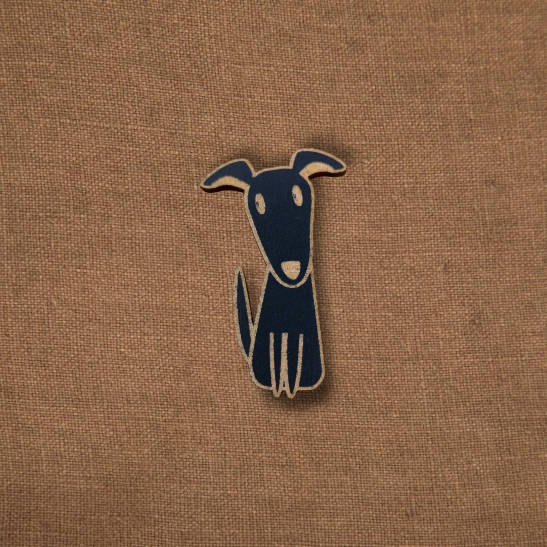 Pregadeira Cão Pêndulo decorativo em forma de cão azul escuro sobre tecido castanho