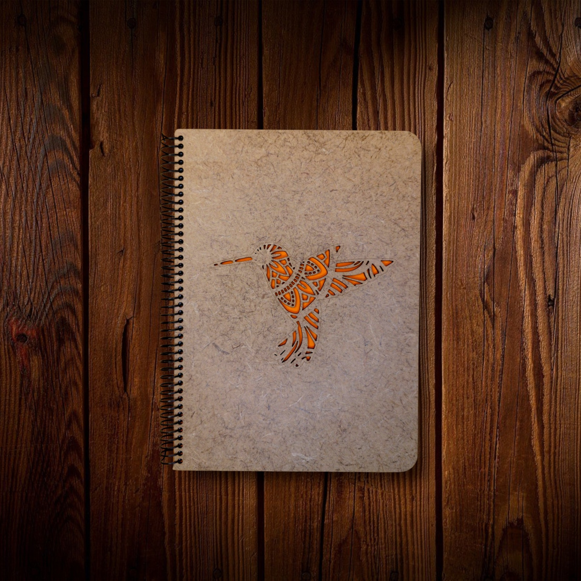 Caderno Beija-flor Caderno com capa cinza e recorte de pássaro decorado em laranja sobre madeira