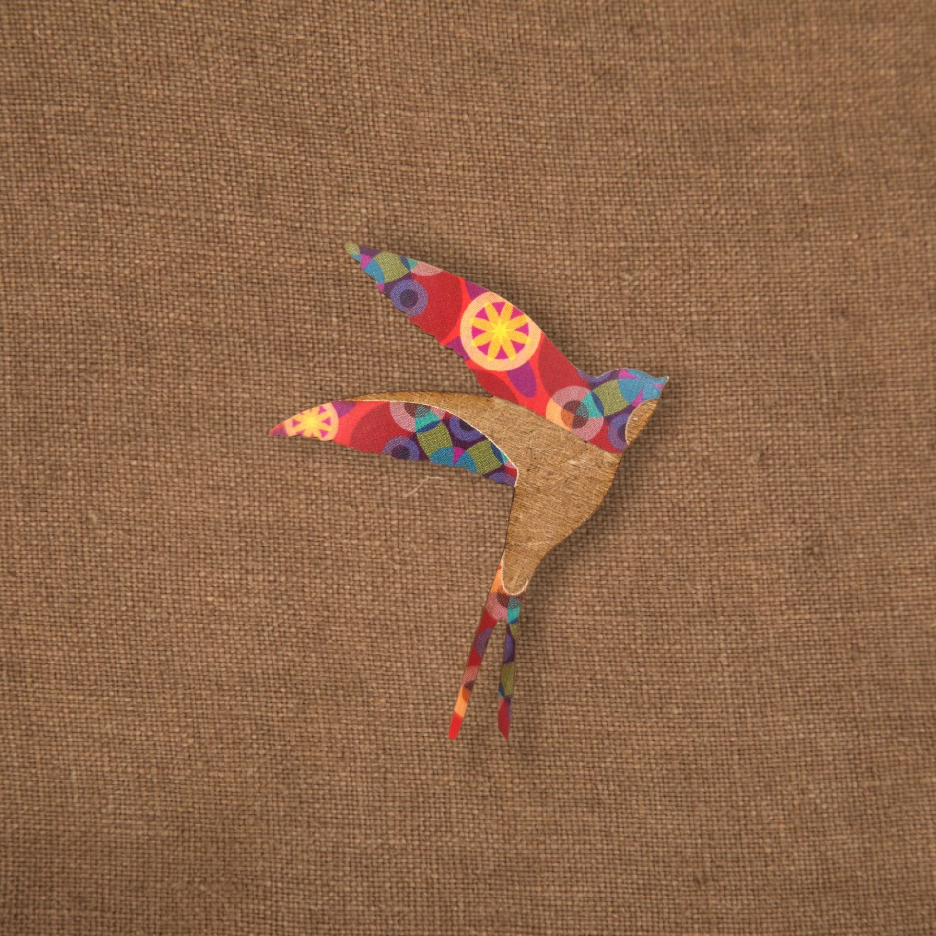 Pregadeira Andorinha Azulejo Pássaro decorativo em tecido colorido e madeira sobre fundo têxtil bege