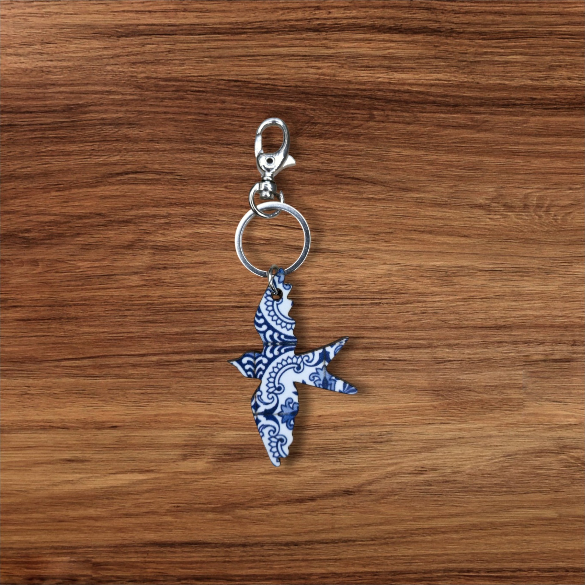 Porta-chaves Andorinha Porta-chaves com pingente de pássaro azul e branco sobre mesa de madeira