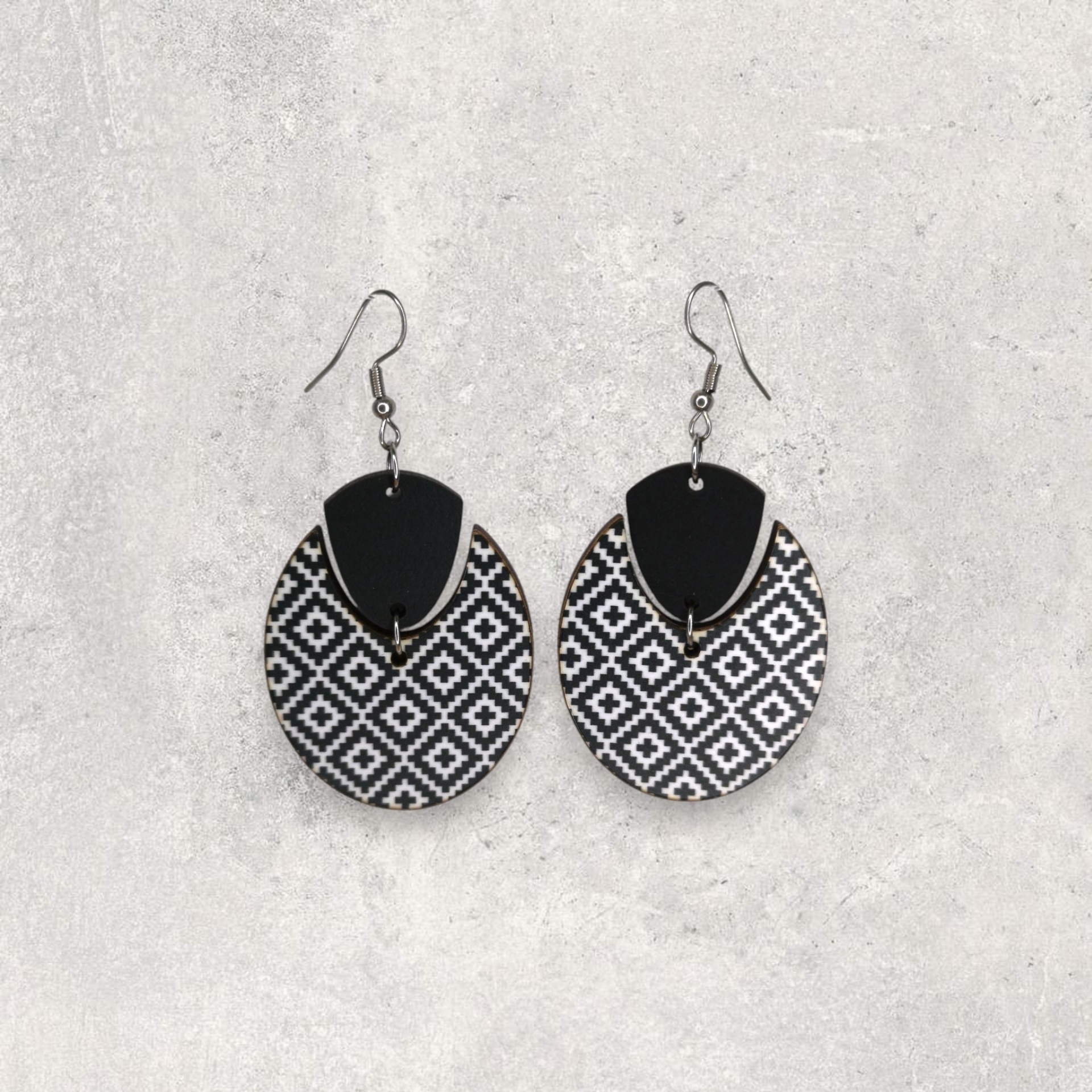 Brincos Oval Brincos pretos e brancos com padrão geométrico sobre fundo cinzento.