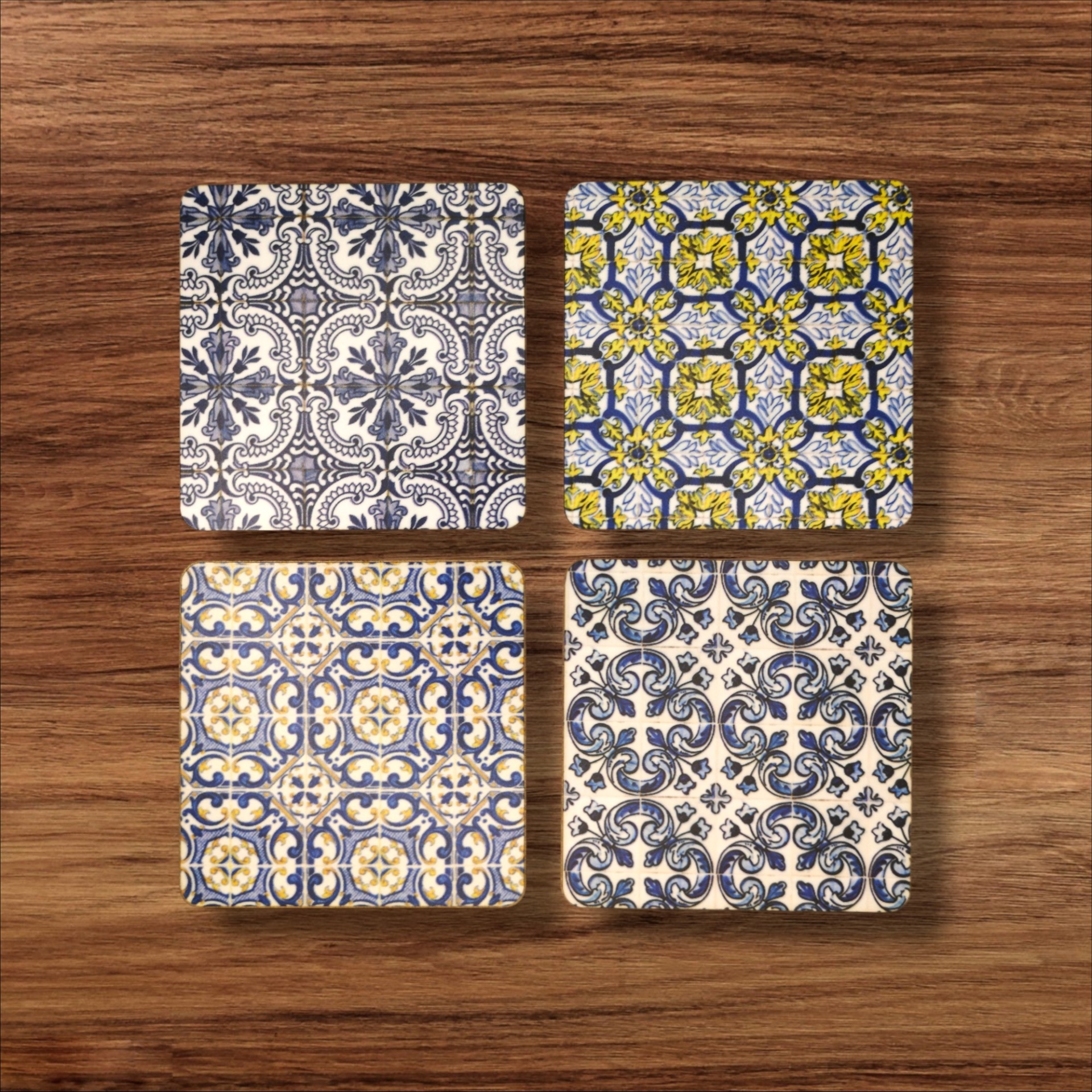 Base de Copos Azulejo Quatro azulejos quadrados com padrões tradicionais em azul, branco e amarelo sobre madeira