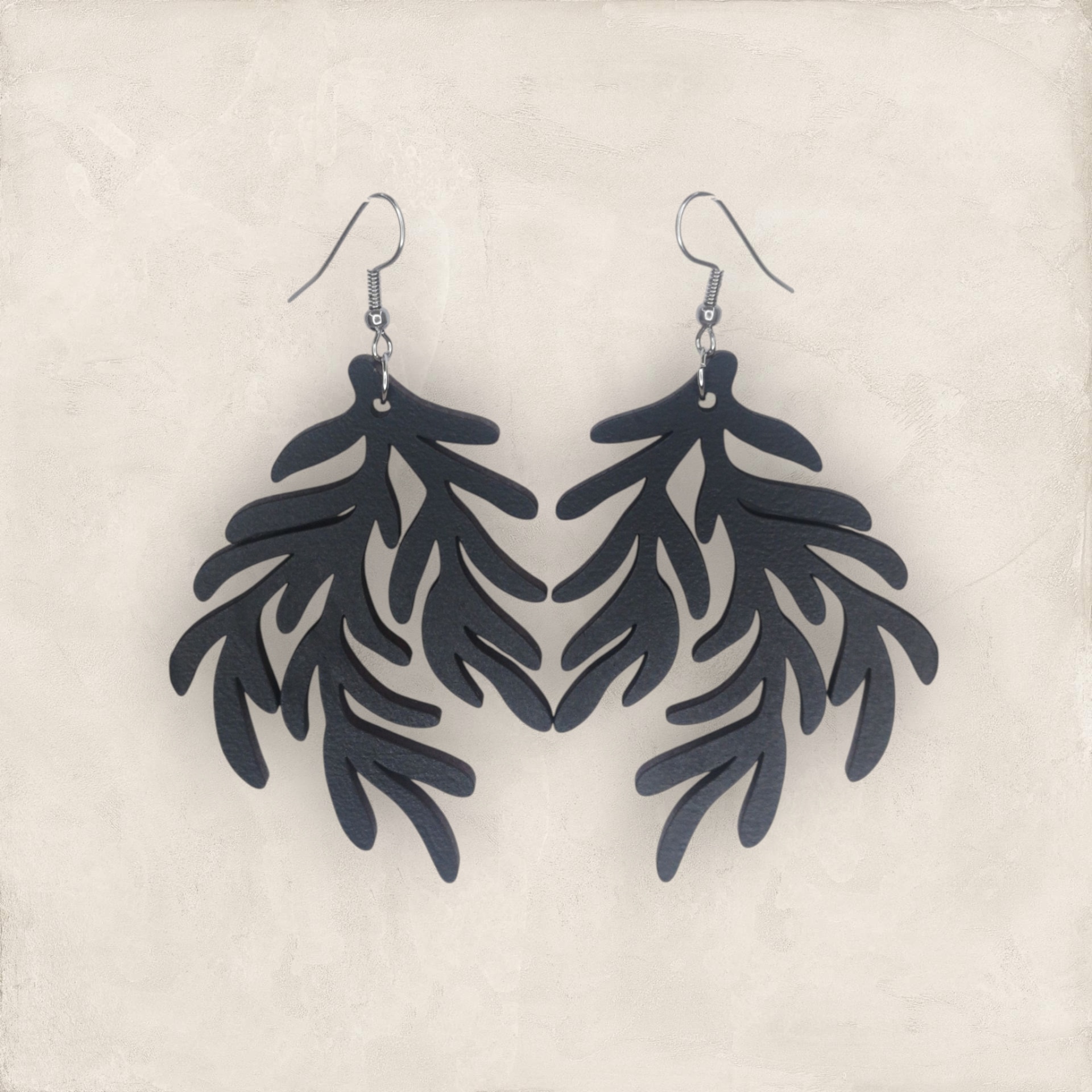 Brincos Rama Brincos pretos em forma de folhas sobre fundo claro