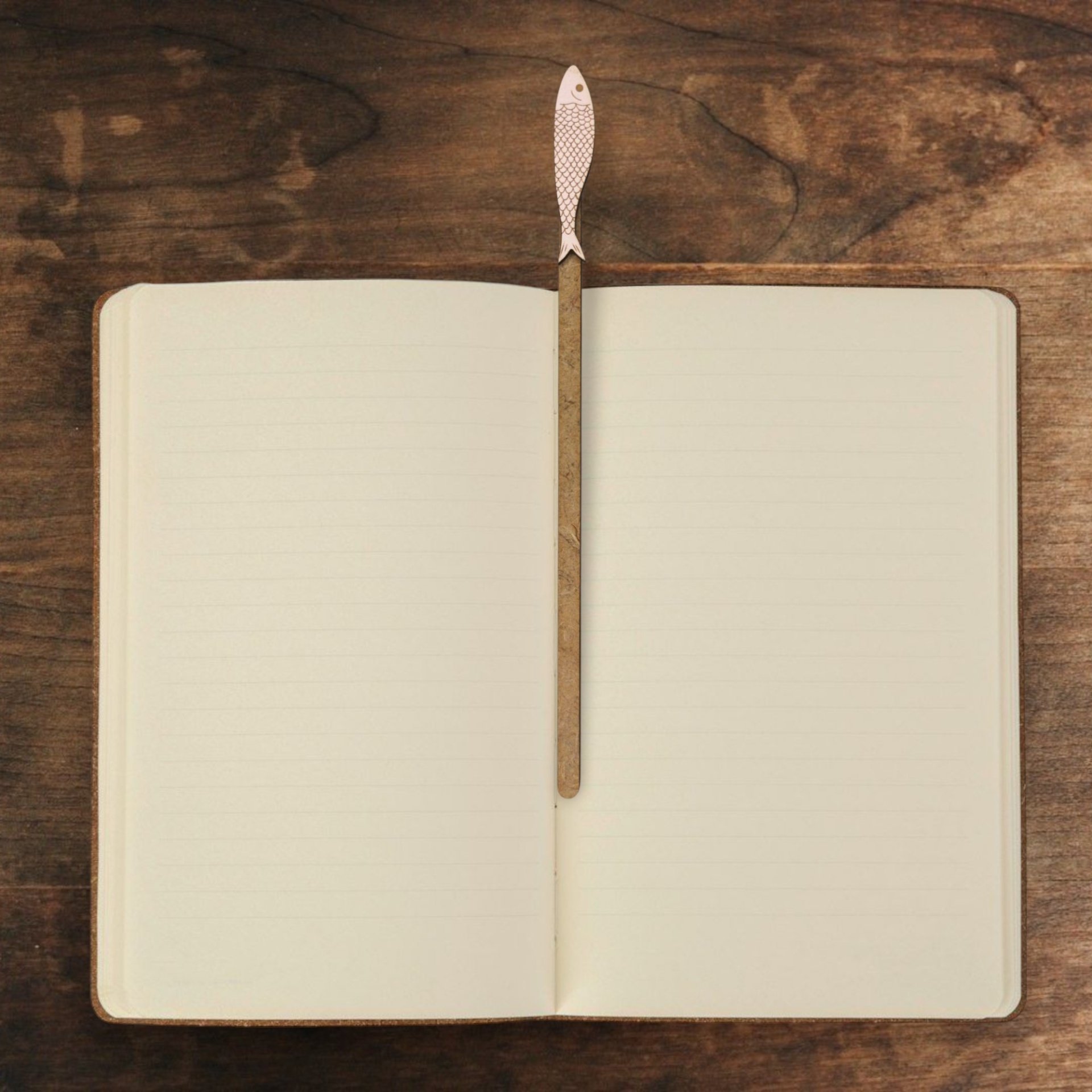 Marcador Sardinha em lata Caderno aberto com marcador de página em forma de peixe sobre superfície de madeira.