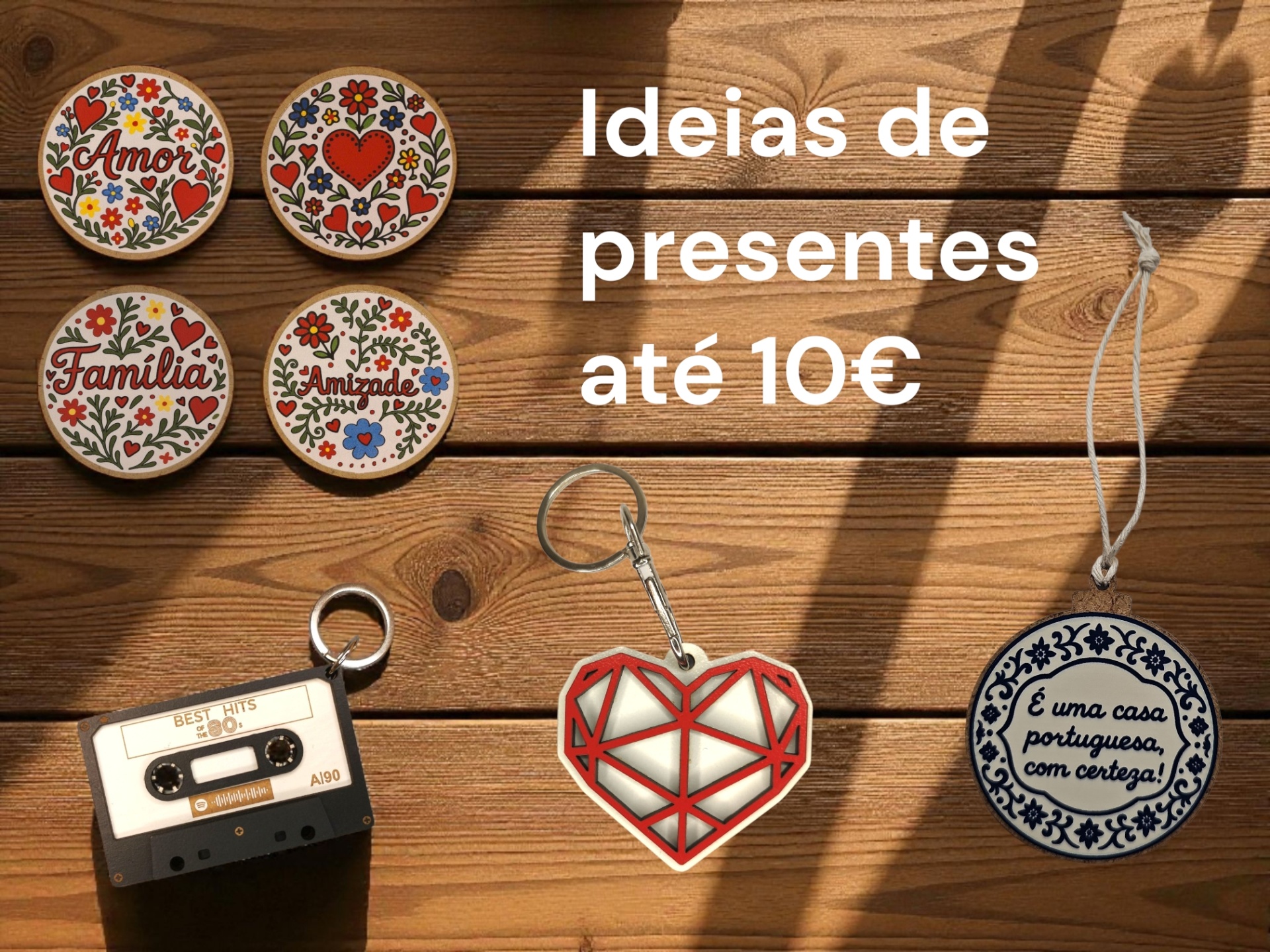 Presentes variados com motivos florais, porta-chaves e ornamento em fundo de madeira com sombra. Texto 'Ideias de presentes até 10€'.
