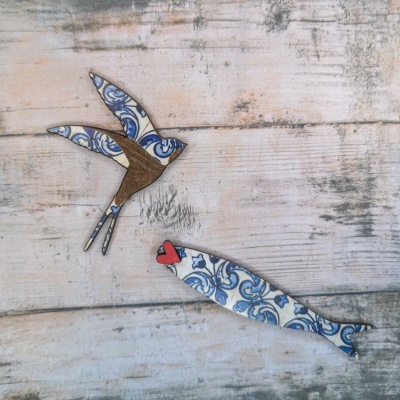 Adornos decorativos de madeira com padrão azulejo azul e branco em forma de pássaro e peixe.