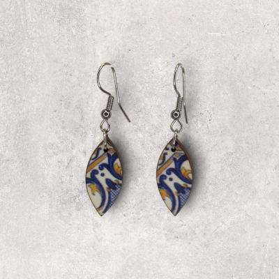 Brincos forma de folha com padrão azul e amarelo sobre fundo cinzento