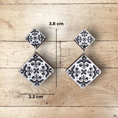 Brincos quadrados preto e branco com padrão sobre madeira clara