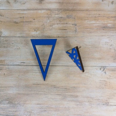 Dois brincos triangulares de madeira azul e natural numa mesa de madeira clara