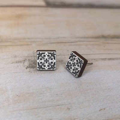 Brincos quadrados com padrão floral preto e branco sobre madeira
