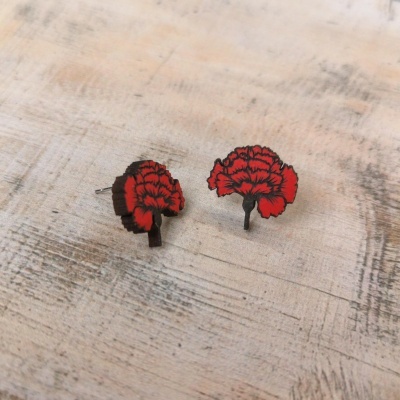 Brincos vermelhos em forma de flor sobre superfície de madeira
