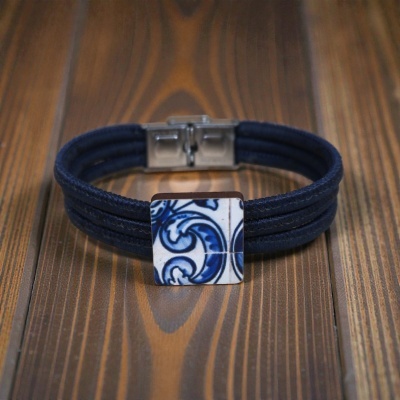 Pulseira azul com centro de azulejo português azul e branco sobre madeira.