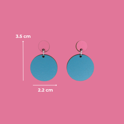 Brincos redondos rosa e azul com medidas sobre Fundo rosa