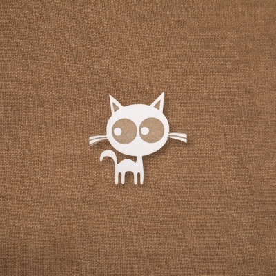 Figura branca de gato estilizado sobre tecido castanho