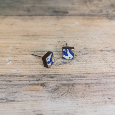 Brincos quadrados com padrão azul, amarelo e branco sobre madeira clara