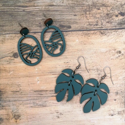 Dois pares de brincos verdes de madeira sobre fundo de madeira clara