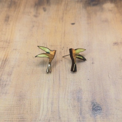 Brincos de madeira em forma de pássaro colorido sobre madeira clara