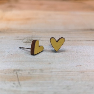 Brincos coração amarelo em madeira sobre mesa clara