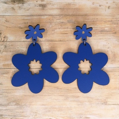 Brincos azuis em forma de flor sobre superfície de madeira clara