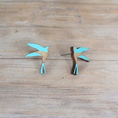Brincos de pino em forma de pássaro em madeira azul e natural sobre madeira clara