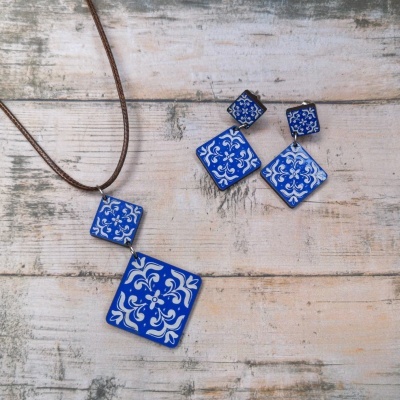 Conjunto de colar e brincos em cerâmica azul com padrão branco sobre fundo de madeira clara
