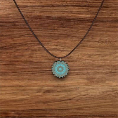 Colar com pendente mandala azul turquesa e castanho sobre madeira