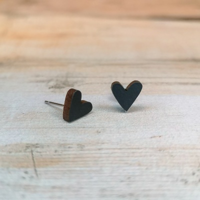 brincos de coração em madeira preta e castanha sobre mesa de madeira clara