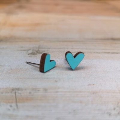 Brincos de coração em madeira azul turquesa com bordas castanhas sobre mesa de madeira clara