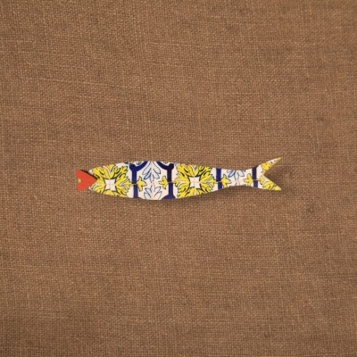 Peixe decorativo em madeira com padrão colorido sobre fundo castanho.