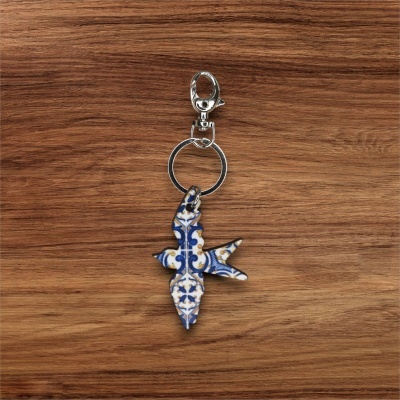 Porta-chaves com pendente de pássaro com padrão azul e amarelo sobre madeira