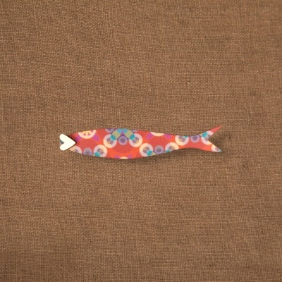 Figura decorativa colorida em forma de peixe sobre tecido castanho