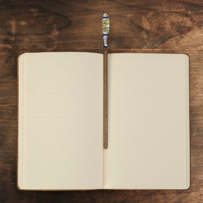 Caderno aberto com folhas pautadas e marcador colorido sobre mesa de madeira