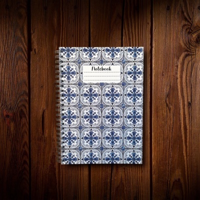 Caderno espiral com capa estampada azul e branca em superfície de madeira escura