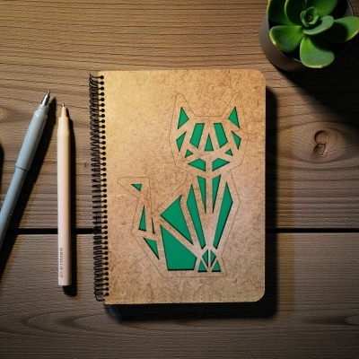 Caderno com capa geométrica de gato, canetas e planta suculenta