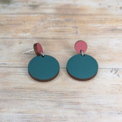 Brincos circulares de madeira verde e rosa antigo sobre fundo de madeira.
