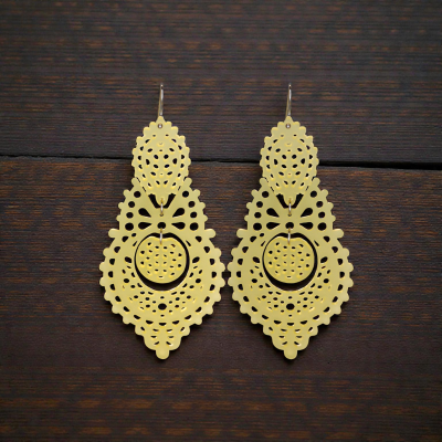 Par de brincos dourados com padrão recortado sobre madeira escura