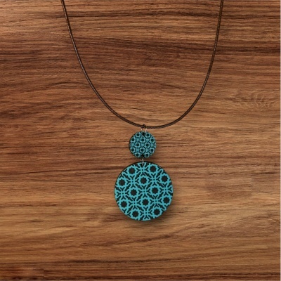 Colar com pendente redondo azul turquesa e preto sobre fundo de madeira