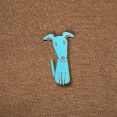 Pin metálico azul em forma de cão estilizado sobre tecido castanho
