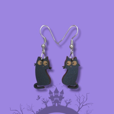 Brincos gato preto em fundo roxo com casa assombrada e árvores