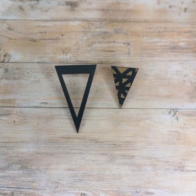 Dois acessórios triangulares em madeira com padrão preto e dourado sobre madeira clara