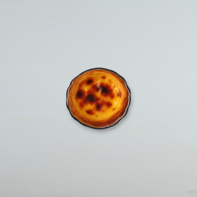 Pastel de nata num prato preto sobre fundo cinzento.