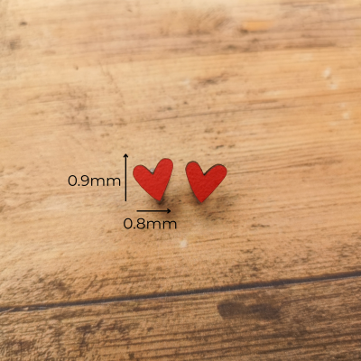 brincos em forma de coração vermelho sobre madeira clara