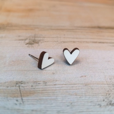 Brincos de coração branco com bordas castanhas sobre fundo de madeira clara