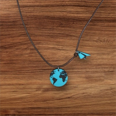 Colar com pendente azul de mapa-múndi e avião de papel sobre fundo de madeira