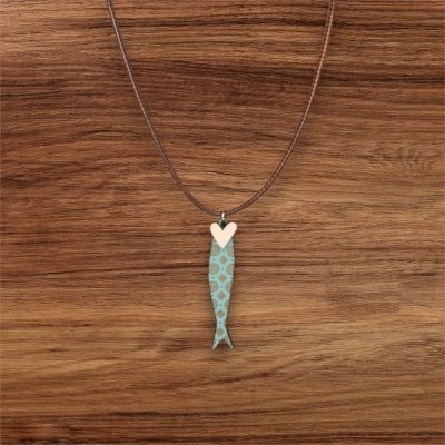 Colar com pendente de peixe azul com coração branco sobre madeira